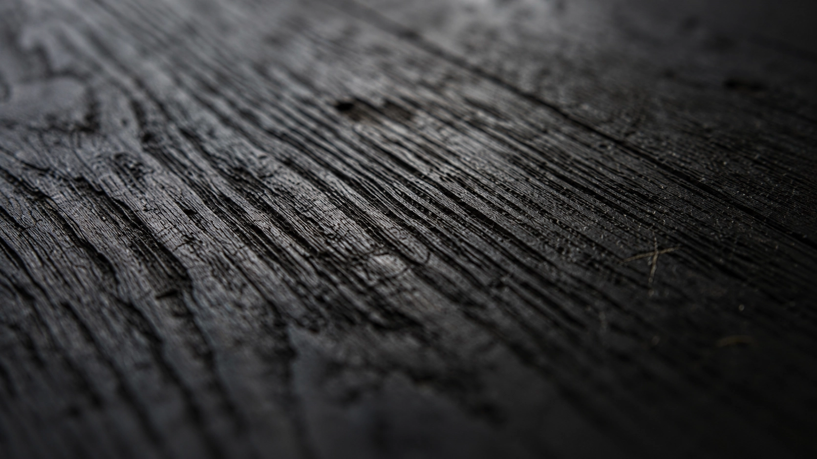 A macro of dark, wire-brushed oak grain with a deep charcoal finish.