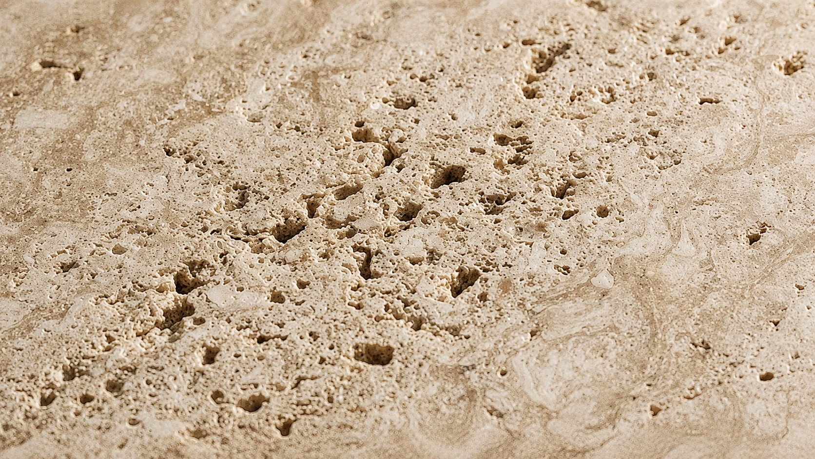 A macro close-up of porous travertine stone in warm beige and cream tones.